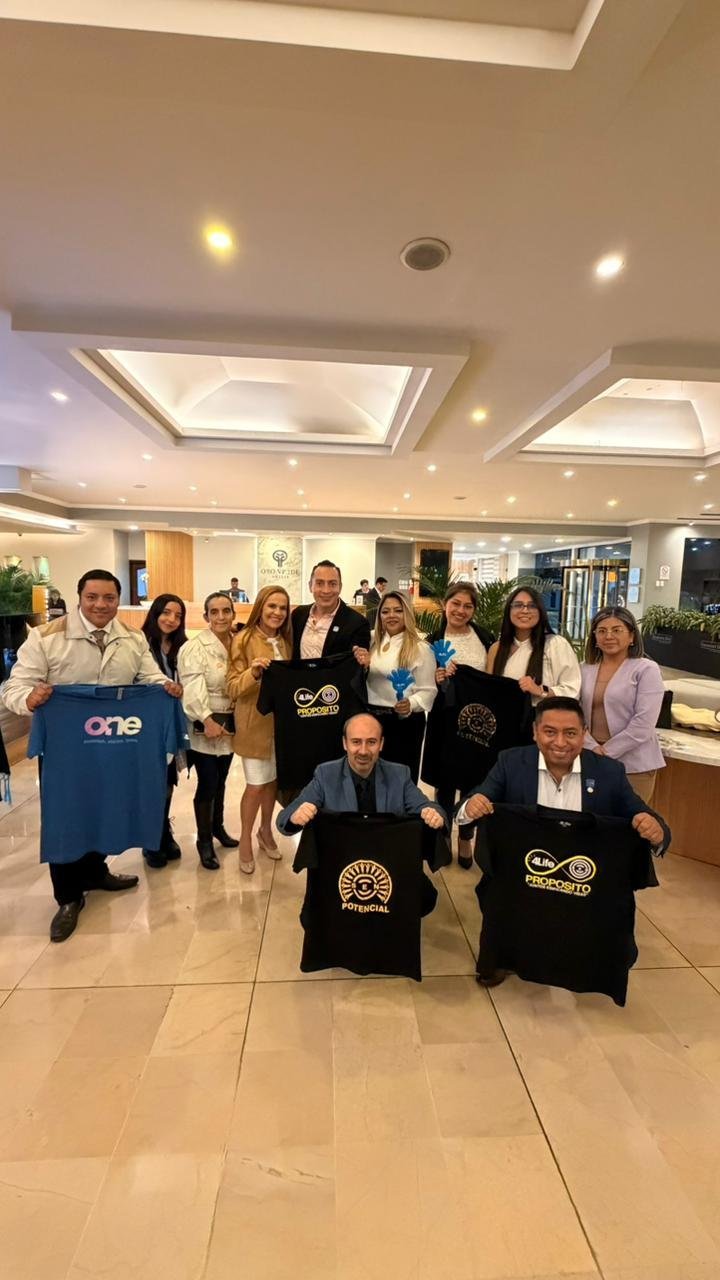 Equipo Regional 4Life Celebración de Éxito 4Life - Grupo del equipo con camisas de marca en interior moderno - Expansión Internacional
