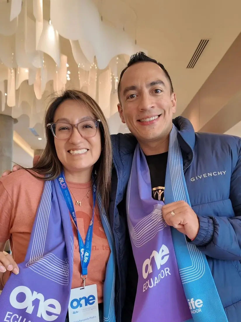 Asistencia a Evento Global Evento de Logros 4Life - Mujer y hombre con lanyards de evento en interior elegante - Equipo de Mentoría Global